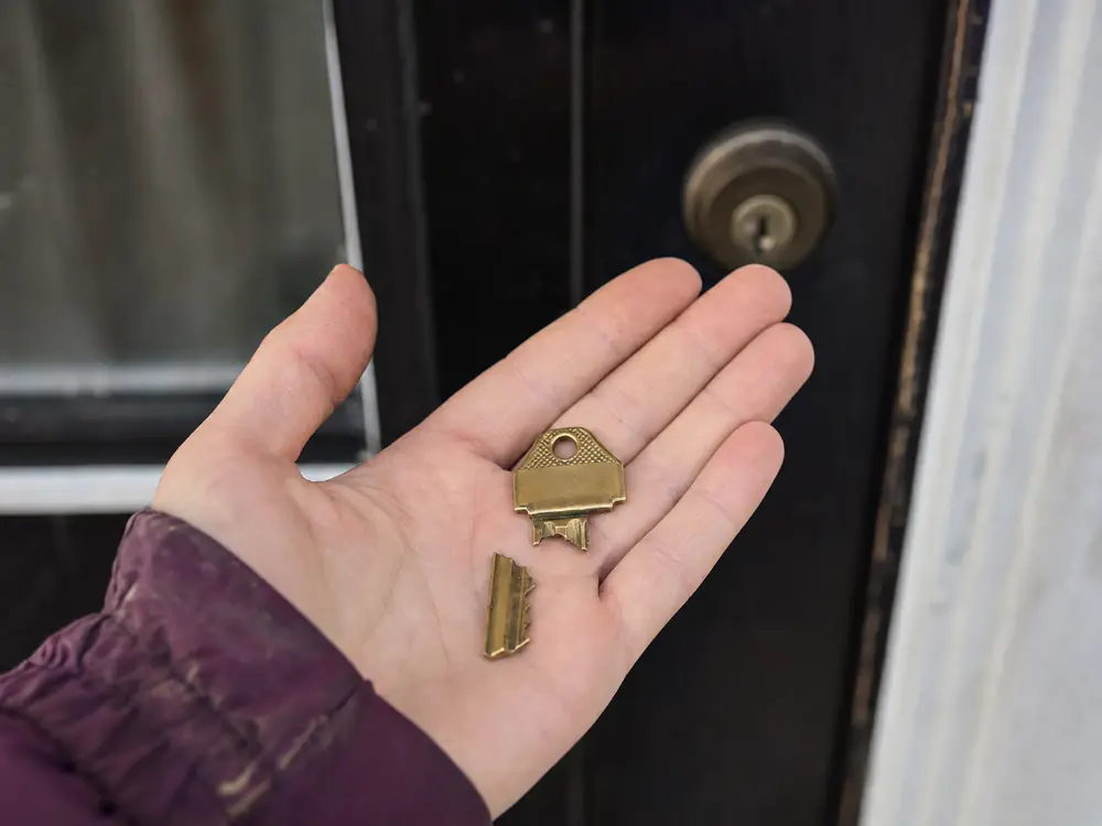 De twee helften van een afgebroken huissleutel in een open hand